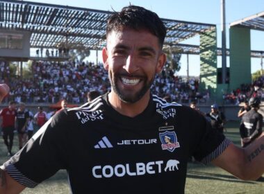 Mauricio Isla con la camiseta de Colo-Colo y los brazos en alto.