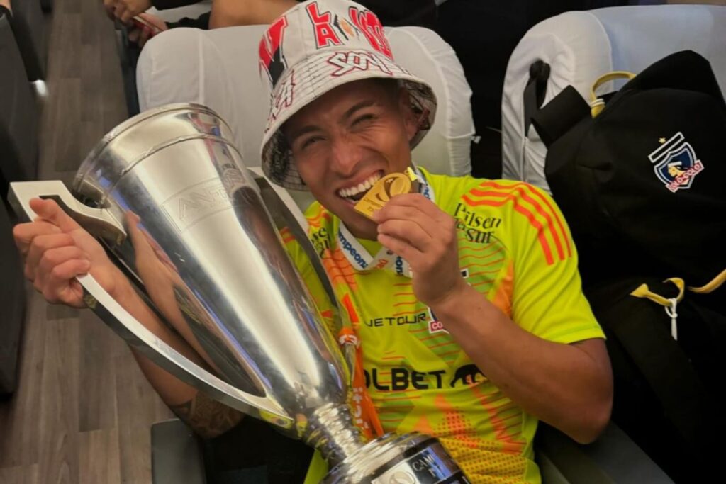 Brayan Cortés mordiendo la medalla de campeón con la copa del Campeonato Nacional.