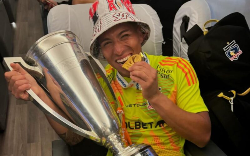 Brayan Cortés mordiendo la medalla de campeón con la copa del Campeonato Nacional.