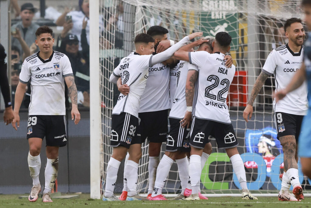 Jugadores de Colo-Colo abrazados celebrando un gol.