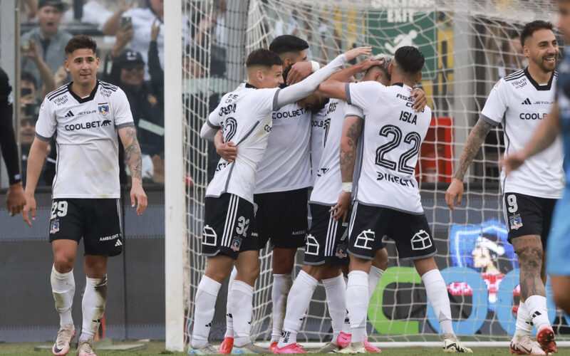 Jugadores de Colo-Colo abrazados celebrando un gol.