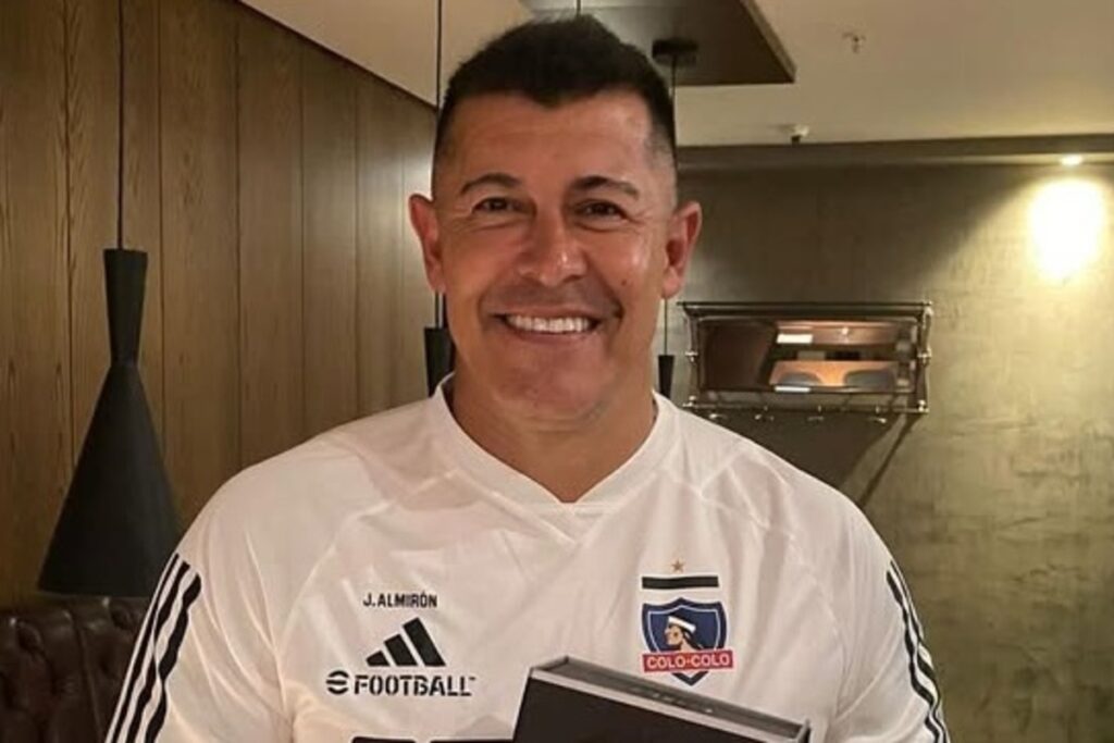 Primer plano de Jorge Almirón sonriente con camiseta de Colo-Colo.