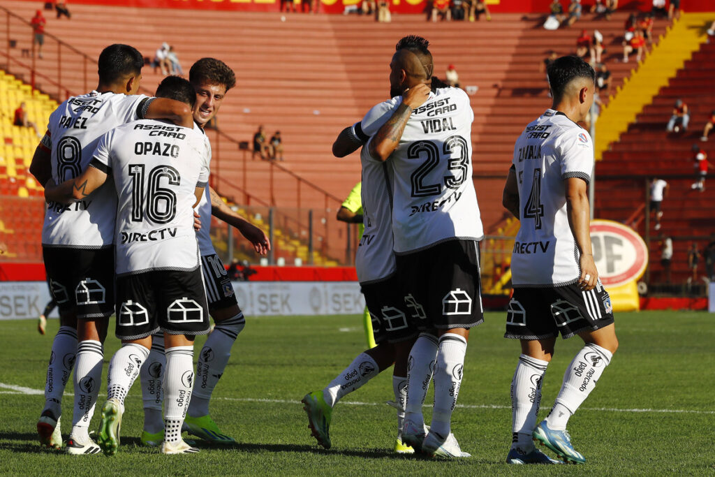 Jugadores de Colo-Colo abrazados celebrando un gol.