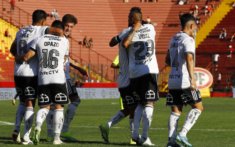 Jugadores de Colo-Colo abrazados celebrando un gol.