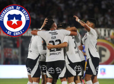 Jugadores de Colo-Colo abrazados junto al escudo de la Selección Chilena.