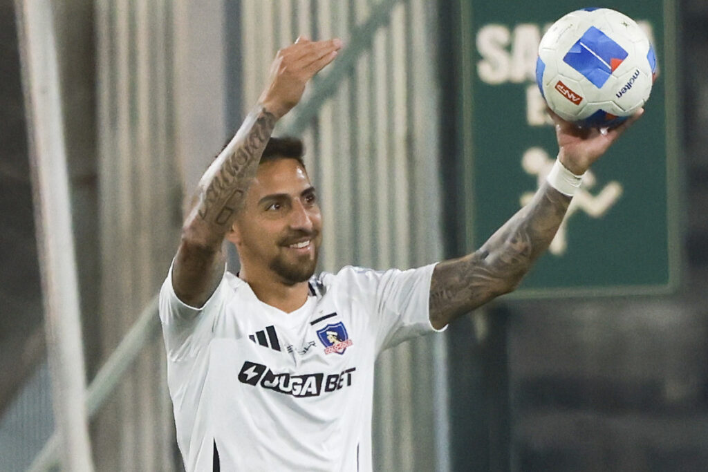 Primer plano de Javier Correa con camiseta de Colo-Colo y una pelota en su mano.