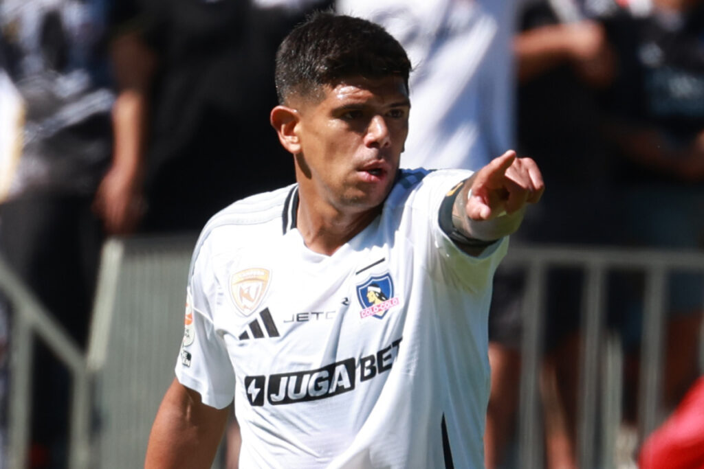 Esteban Pavez con camiseta de Colo-Colo y apuntando con el dedo.